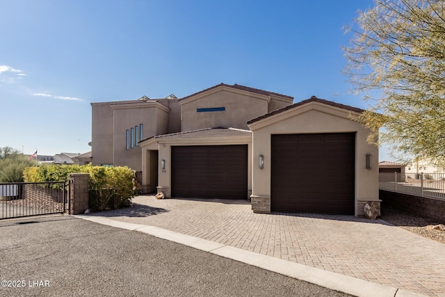 view of front facade with decorative driveway, stucco siding, fence, a garage, and a tiled roof