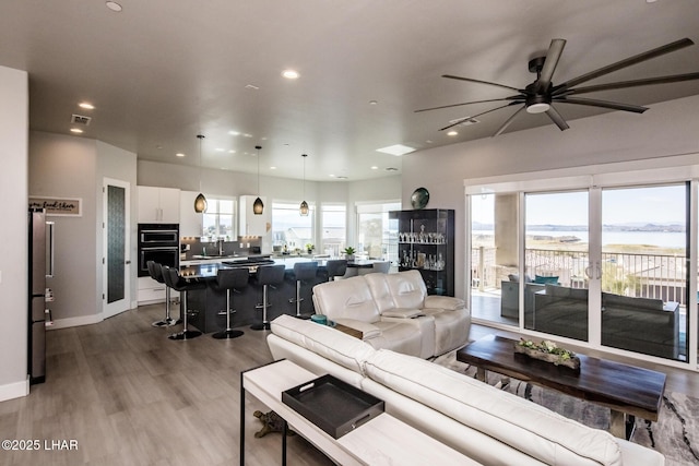 living area with light wood-style floors, recessed lighting, visible vents, and plenty of natural light