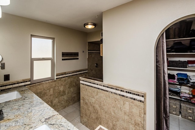 bathroom featuring tile walls, vanity, tile patterned floors, and walk in shower