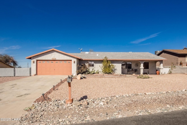 ranch-style home with driveway, an attached garage, fence, and stucco siding