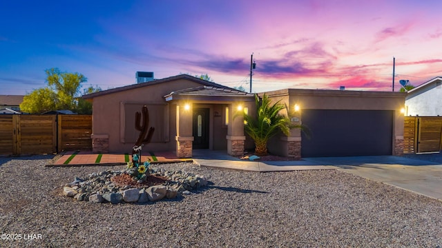 view of front of home featuring fence, stone siding, stucco siding, concrete driveway, and an attached garage