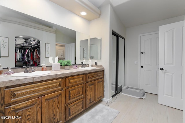 bathroom with a stall shower, a walk in closet, a sink, and double vanity