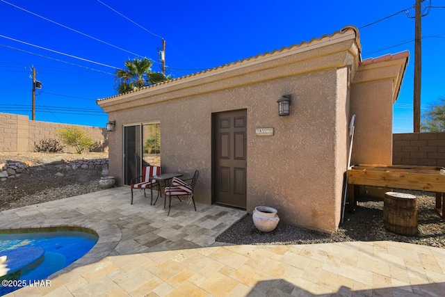 exterior space with a patio area, fence, a tiled roof, and stucco siding