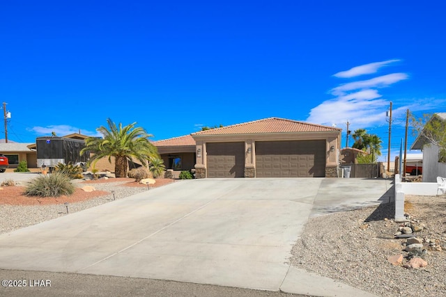 view of front of home featuring a garage, a tiled roof, stone siding, driveway, and stucco siding