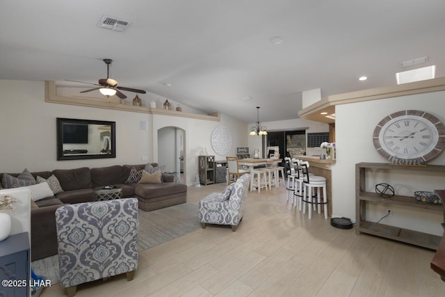 living room featuring visible vents, arched walkways, lofted ceiling, wood finished floors, and ceiling fan with notable chandelier