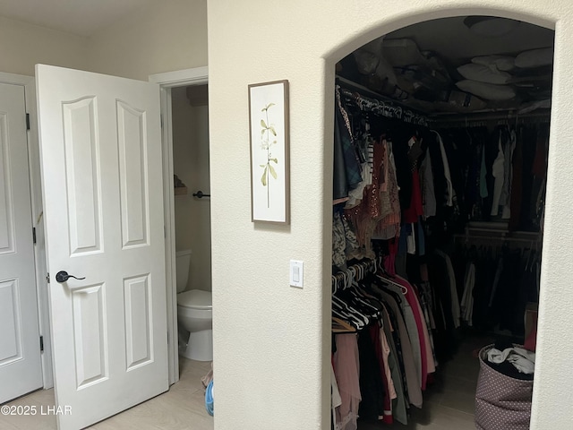 walk in closet featuring arched walkways