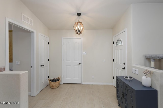 foyer entrance with a chandelier, light wood finished floors, visible vents, and baseboards