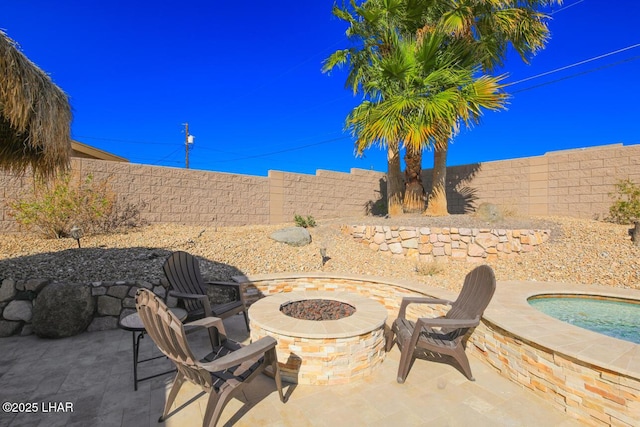 view of patio / terrace with an outdoor fire pit, a fenced backyard, and a hot tub