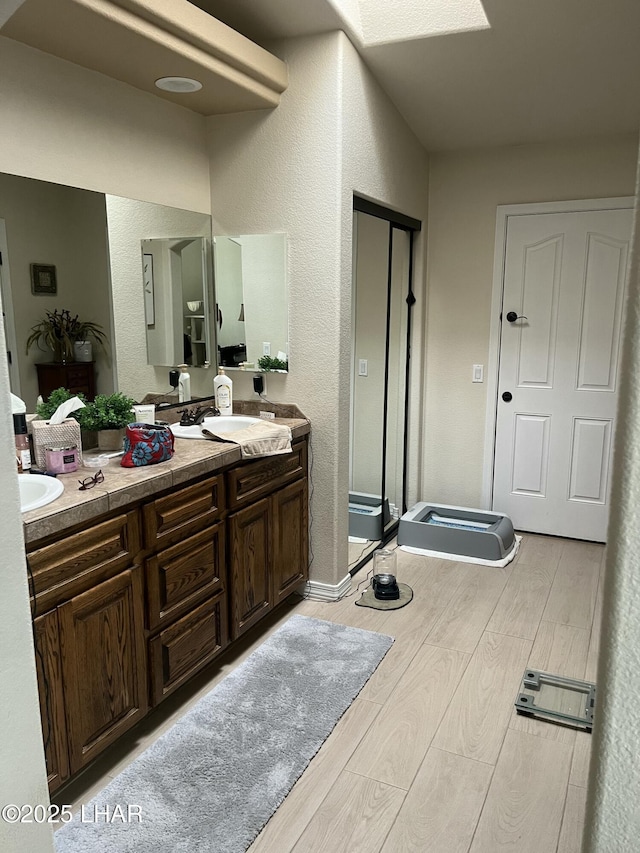 bathroom featuring double vanity, a shower stall, a sink, and wood finished floors