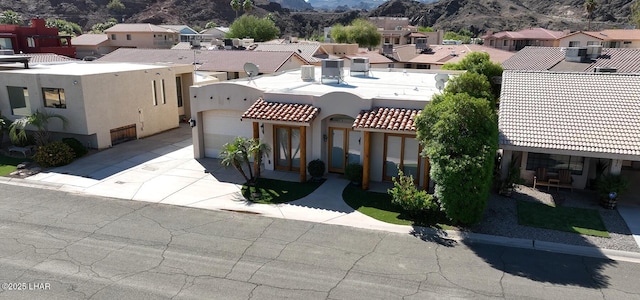 view of front of house featuring stucco siding, an attached garage, a mountain view, driveway, and a residential view
