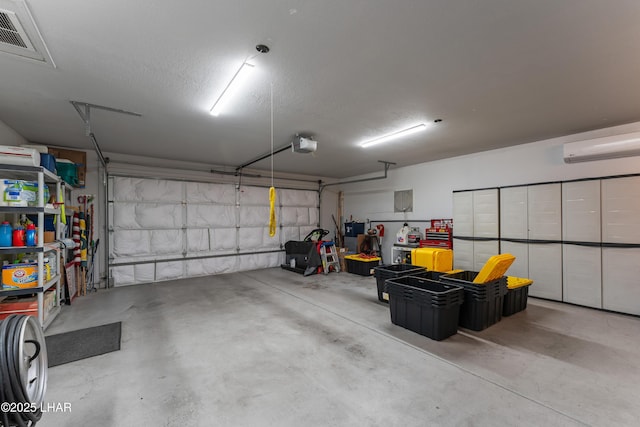 garage with a wall mounted air conditioner and a garage door opener