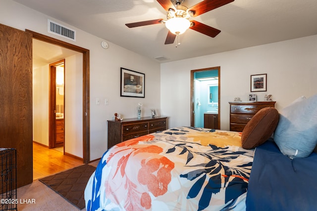 bedroom with ceiling fan, connected bathroom, and light hardwood / wood-style flooring