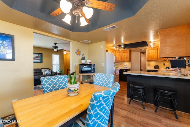 dining room featuring ceiling fan, light hardwood / wood-style floors, and a textured ceiling