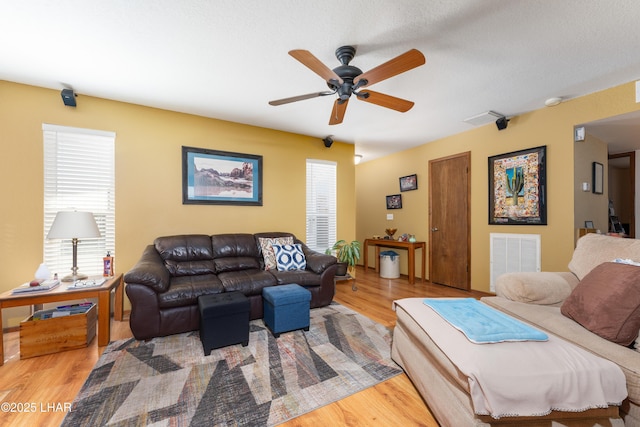 living room featuring hardwood / wood-style flooring, ceiling fan, and a textured ceiling