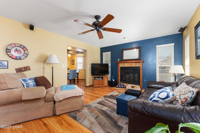 living room featuring hardwood / wood-style flooring, ceiling fan, and a tile fireplace