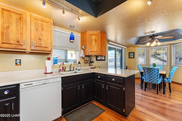 kitchen with sink, hanging light fixtures, white dishwasher, kitchen peninsula, and light wood-type flooring