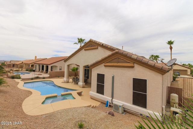 rear view of house with a patio area, fence, a pool with connected hot tub, and stucco siding