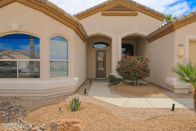 entrance to property with stucco siding and a tile roof