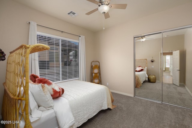 carpeted bedroom with visible vents, a closet, baseboards, and a ceiling fan