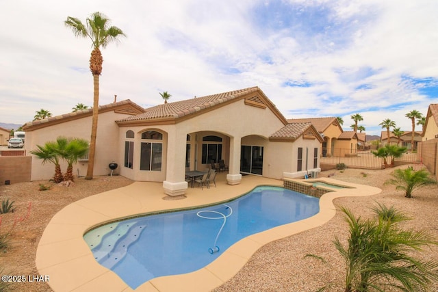 view of pool with a patio area, a pool with connected hot tub, and fence