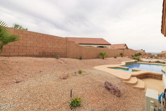 view of yard featuring a fenced backyard and a pool with connected hot tub
