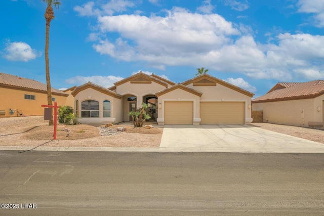 mediterranean / spanish home with a tiled roof, a garage, stucco siding, and concrete driveway