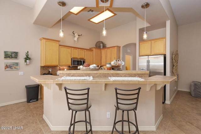 kitchen featuring tasteful backsplash, visible vents, a kitchen breakfast bar, and appliances with stainless steel finishes