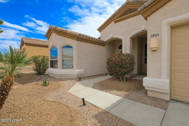 property entrance featuring a tile roof and stucco siding