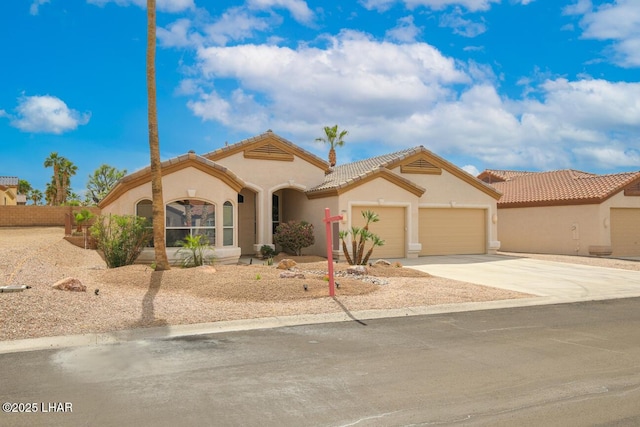 mediterranean / spanish house featuring a tile roof, an attached garage, stucco siding, and concrete driveway