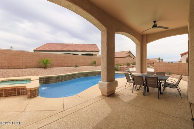 view of swimming pool featuring ceiling fan, a pool with connected hot tub, a fenced backyard, outdoor dining space, and a patio