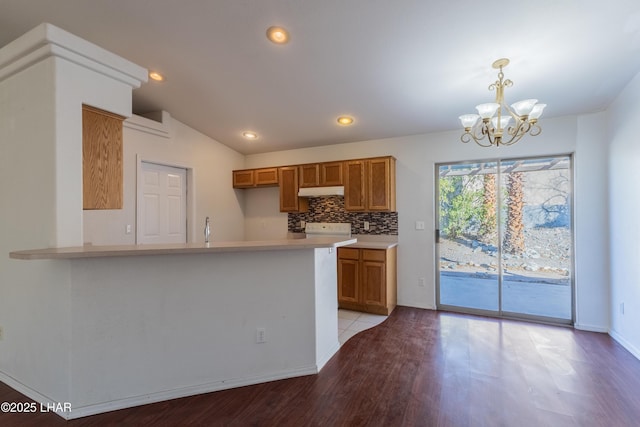 kitchen featuring brown cabinets, a peninsula, light countertops, and lofted ceiling