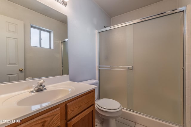 bathroom featuring tile patterned floors, toilet, a stall shower, and vanity