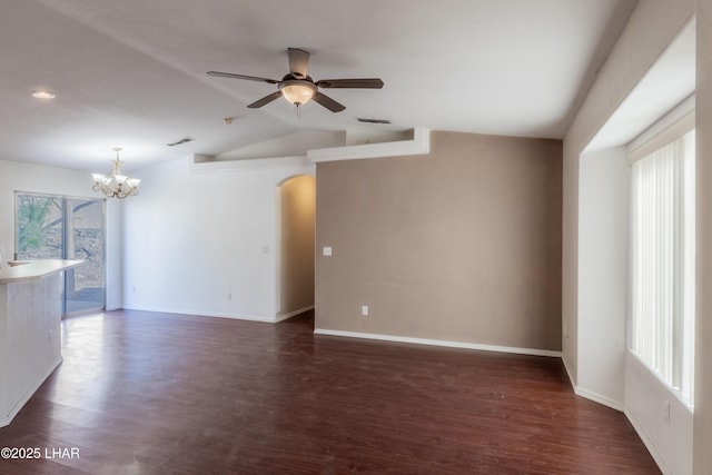 empty room with visible vents, lofted ceiling, ceiling fan with notable chandelier, arched walkways, and dark wood-style floors