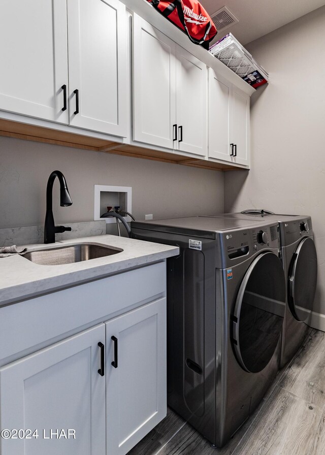 laundry room with cabinets, hardwood / wood-style floors, sink, and washing machine and dryer