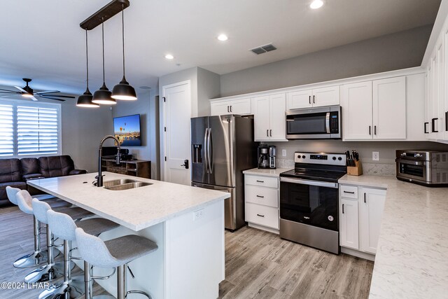 kitchen with white cabinetry, appliances with stainless steel finishes, sink, and pendant lighting