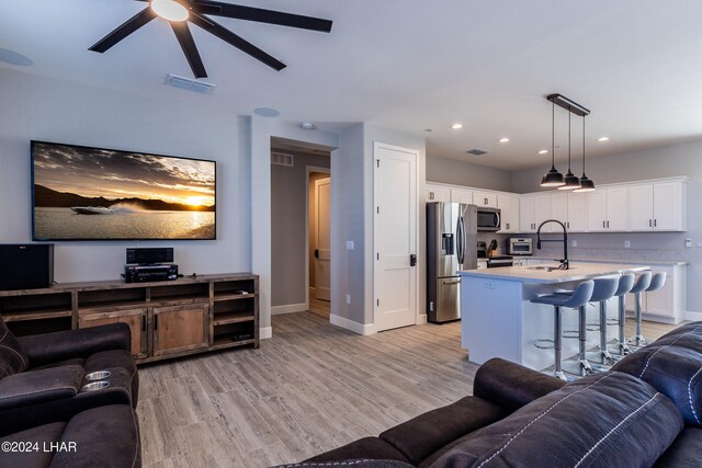 living room featuring sink, ceiling fan, and light wood-type flooring