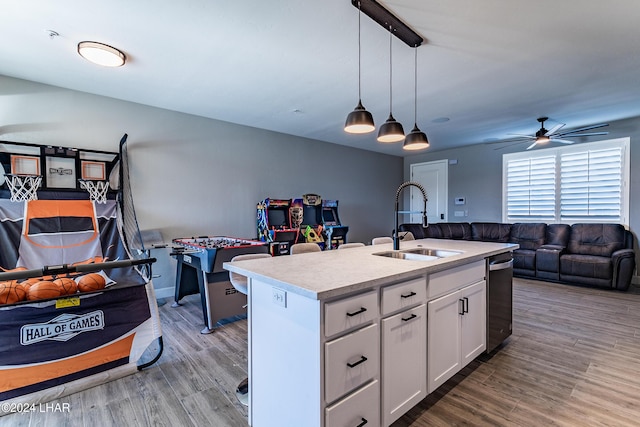 kitchen with pendant lighting, white cabinetry, an island with sink, sink, and light hardwood / wood-style floors