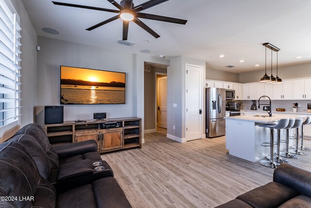 living room featuring sink, light hardwood / wood-style flooring, and ceiling fan