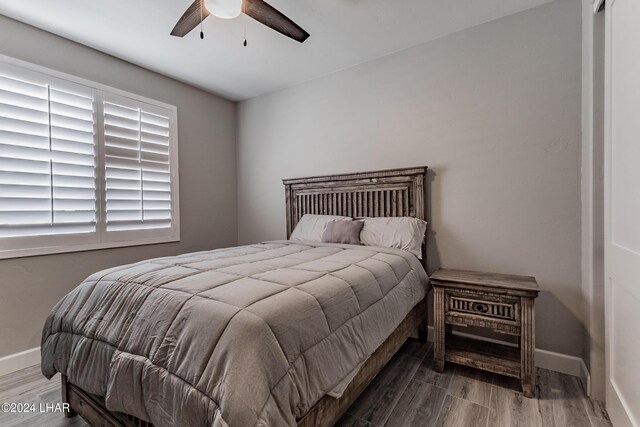 bedroom with multiple windows, wood-type flooring, and ceiling fan