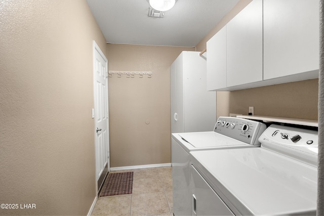 clothes washing area with visible vents, baseboards, light tile patterned flooring, cabinet space, and independent washer and dryer