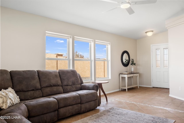 living area featuring light tile patterned floors, a ceiling fan, and baseboards