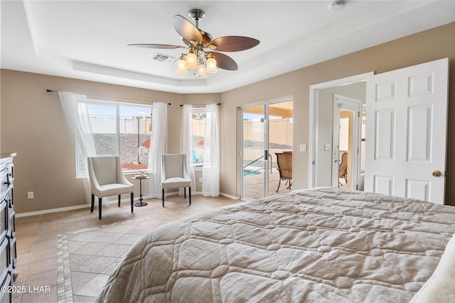 bedroom with light tile patterned floors, a tray ceiling, visible vents, and access to exterior