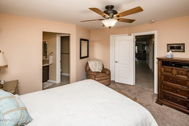 bedroom featuring ceiling fan, light colored carpet, and connected bathroom