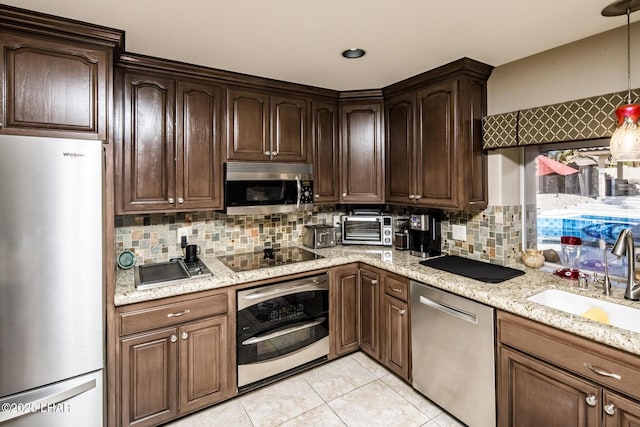 kitchen with light tile patterned flooring, sink, backsplash, stainless steel appliances, and light stone countertops