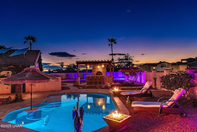 pool at dusk featuring a pergola, a fire pit, a patio, and an outdoor fireplace