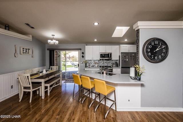 kitchen with fridge, white cabinets, a kitchen breakfast bar, and dark hardwood / wood-style floors