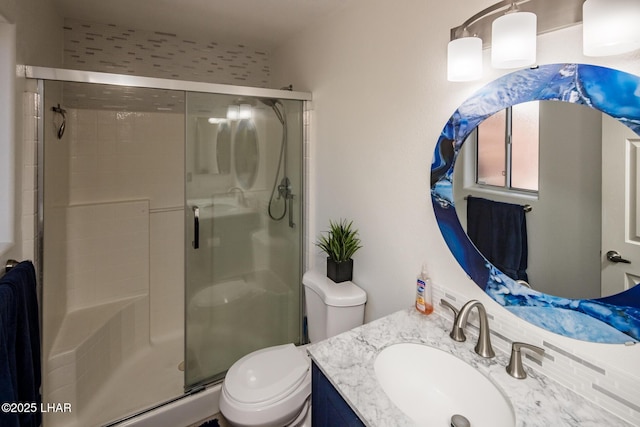 bathroom featuring toilet, vanity, and a shower with shower door