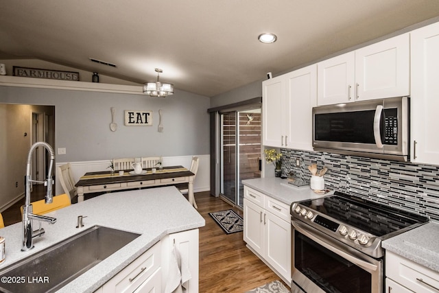 kitchen featuring appliances with stainless steel finishes, sink, lofted ceiling, white cabinets, and hanging light fixtures