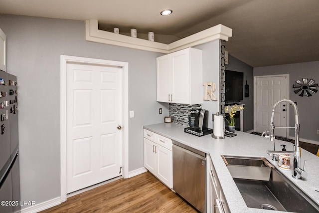 kitchen with white cabinetry, light wood-type flooring, sink, tasteful backsplash, and appliances with stainless steel finishes