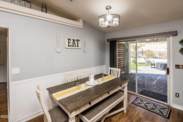 dining space featuring an inviting chandelier, vaulted ceiling, and dark wood-type flooring